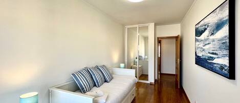 A bedroom with a bed, bedside table, and a painting on the wall.