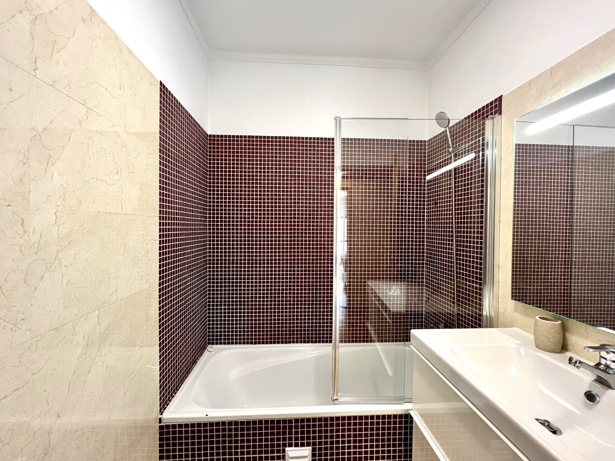 Un bagno moderno con doccia vetrata, una vasca da bagno bianca e un grande specchio sopra il lavabo.