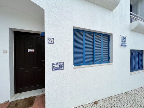 A white building with a black door, blue shutters, and numbered signs. - Albufeira Sunset With Pool by Homing (Albufeira)