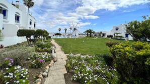 A pathway leading to a white building with a windmill in the background. - Albufeira Sunset With Pool by Homing (Albufeira)