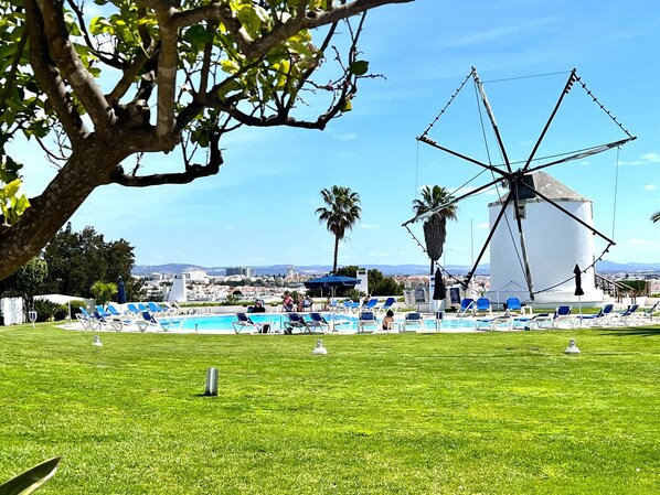 A windmill, a pool, and lounge chairs in a sunny outdoor setting. - Albufeira Sunset With Pool by Homing (Albufeira)