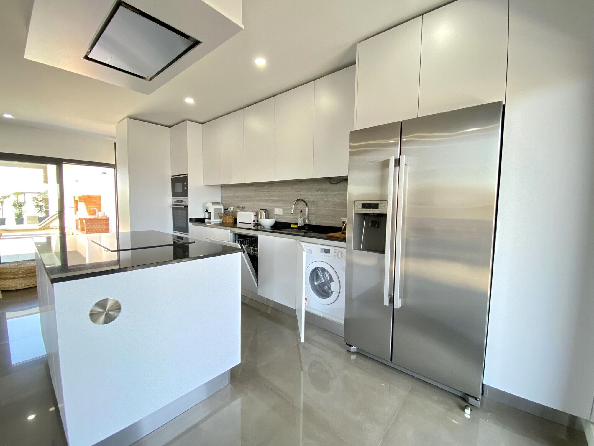 A modern kitchen with stainless steel appliances, a dishwasher, and a built-in washing machine.