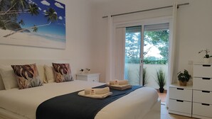A bedroom with a large bed, a nightstand, a dresser, and a view of the outdoors through a sliding glass door. - Albufeira Valley 2 With Pool by Homing (Albufeira)
