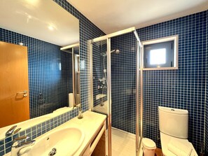 A bathroom with a large bathtub, a glass-enclosed shower, and a toilet.