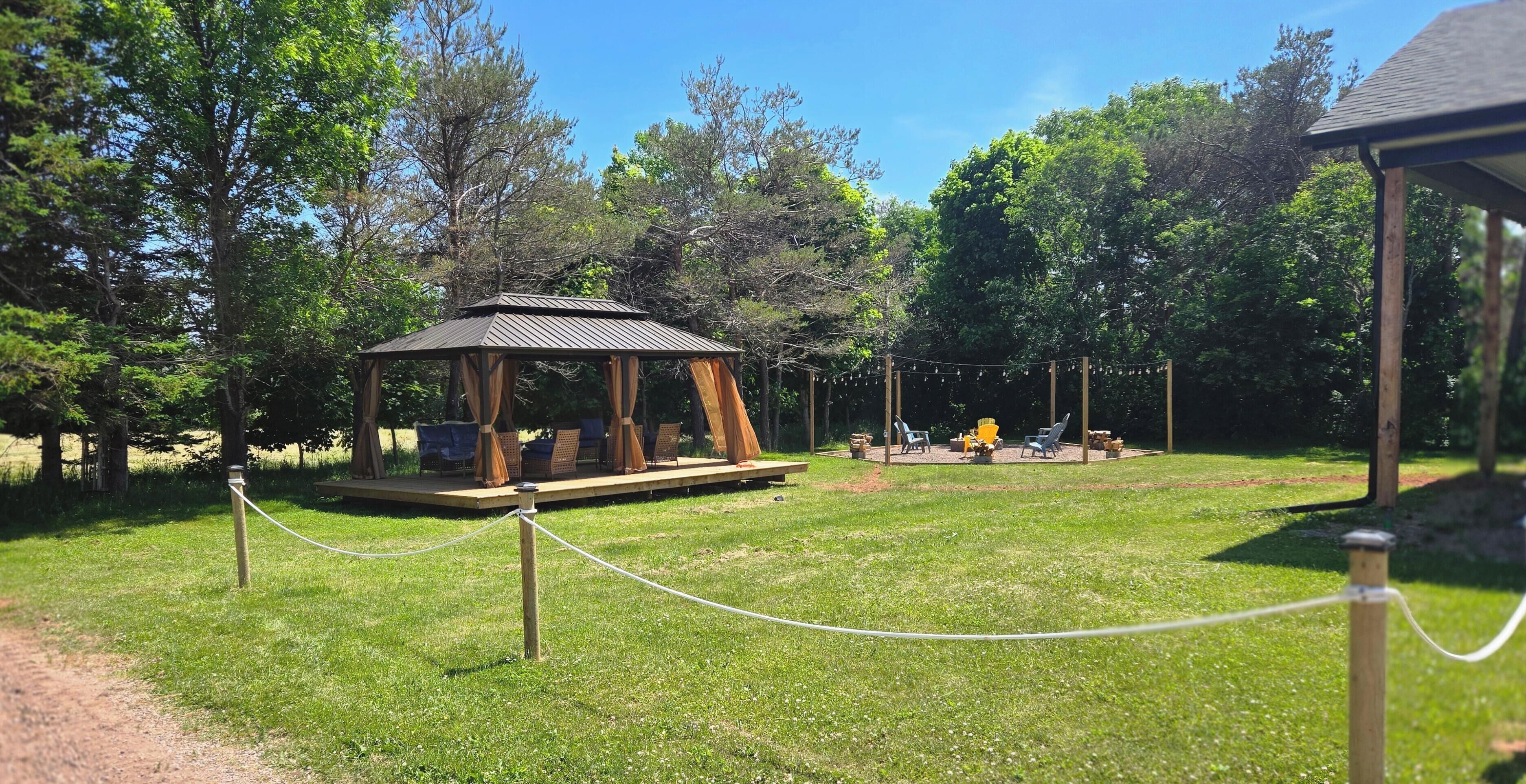 Un belvédère doté d’une terrasse en bois et de sièges, entouré d’une pelouse agrémentée d’arbres.