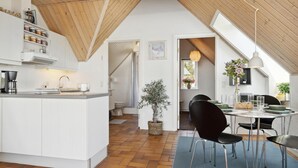 Una cocina moderna con armarios blancos, una isla central y un comedor con mesa y sillas.