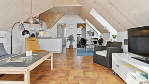 Un amplio loft con techo alto, espacio para cocinar, zona de comedor y área de estar con televisor.