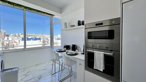 A modern kitchen with a city view, stainless steel appliances, and a minimalist design. - Faro Deluxe by Homing (Faro)