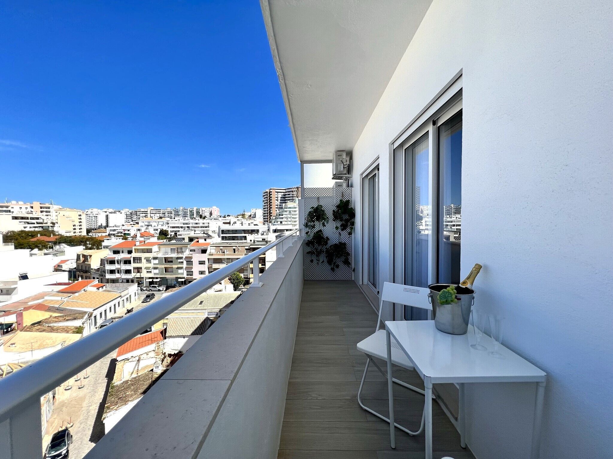 A balcony with a white table, a chair, and a bottle of champagne.