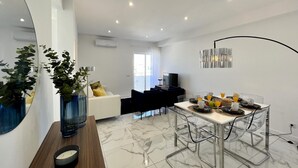 A modern dining area with a marble floor, a dining table set with chairs, and a large mirror on the left. - Faro Deluxe by Homing (Faro)