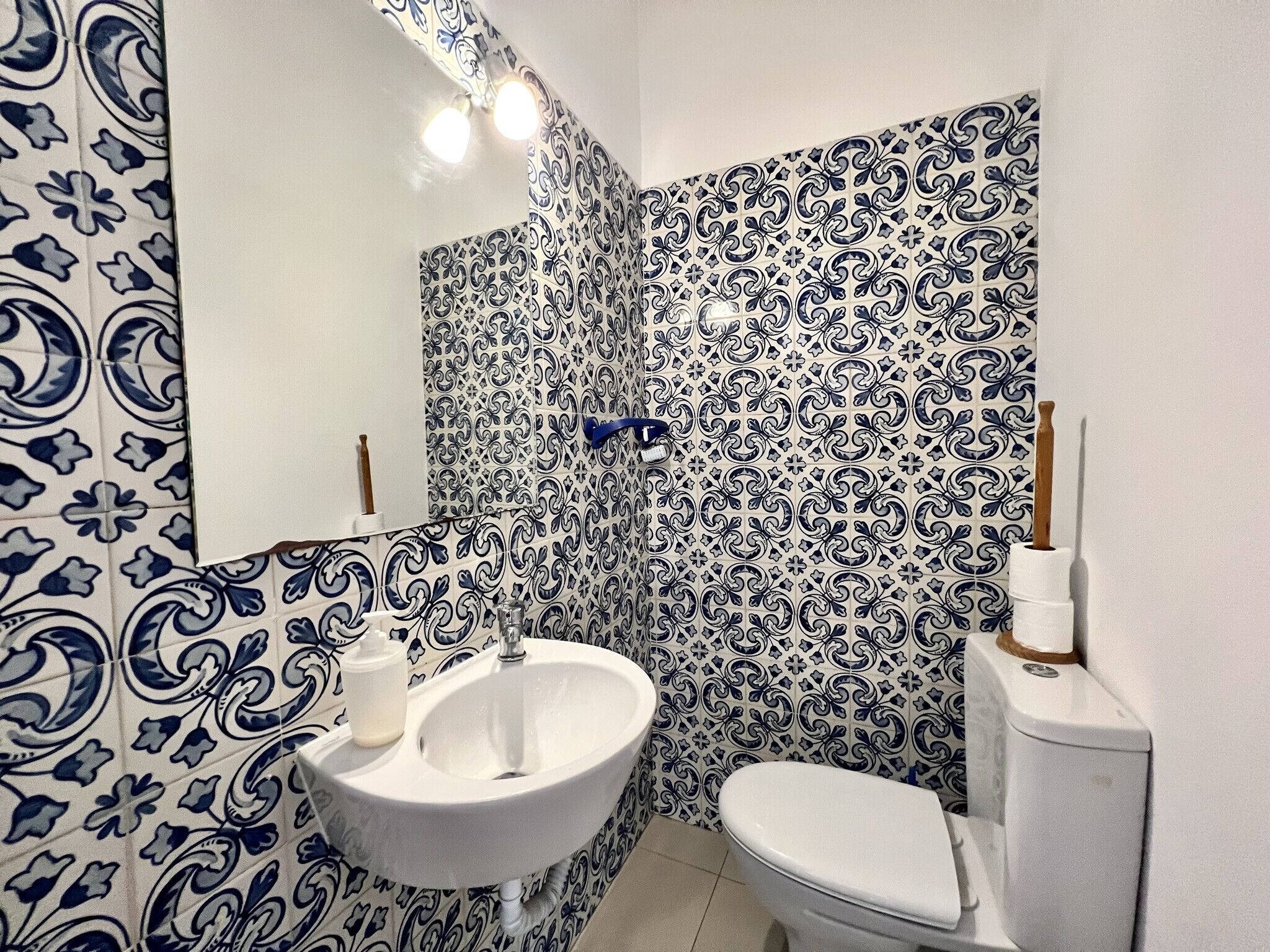 A bathroom with a sink, toilet, and decorative blue and white tiles.