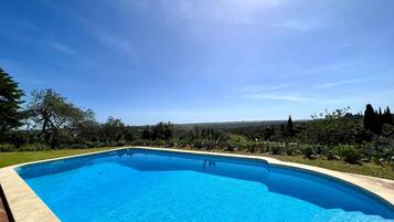 Relax by the pool surrounded by lush greenery and a scenic hilly view.