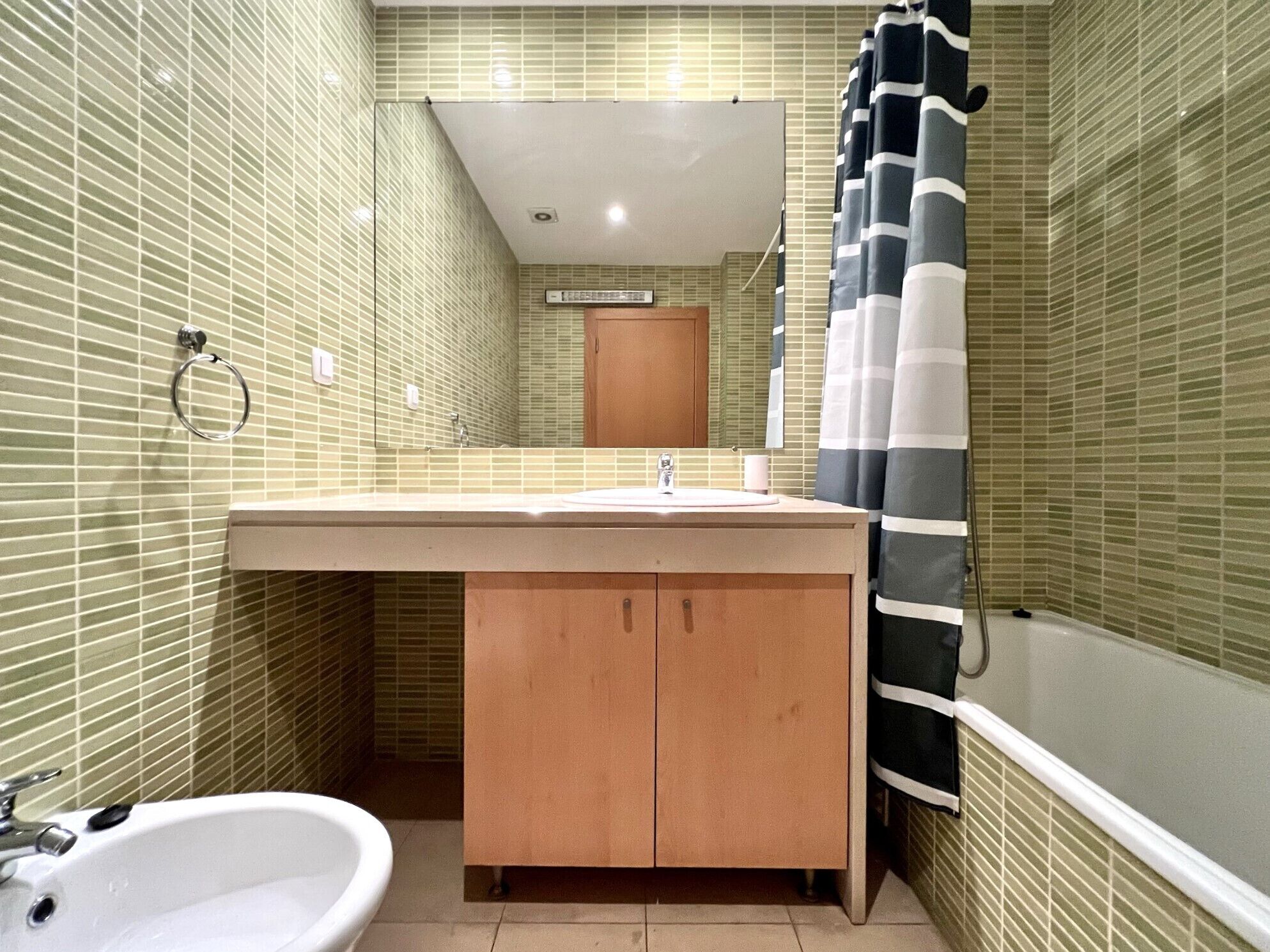 A bathroom with a sink, mirror, and bathtub.