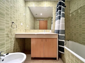 A bathroom with a sink, mirror, and bathtub.