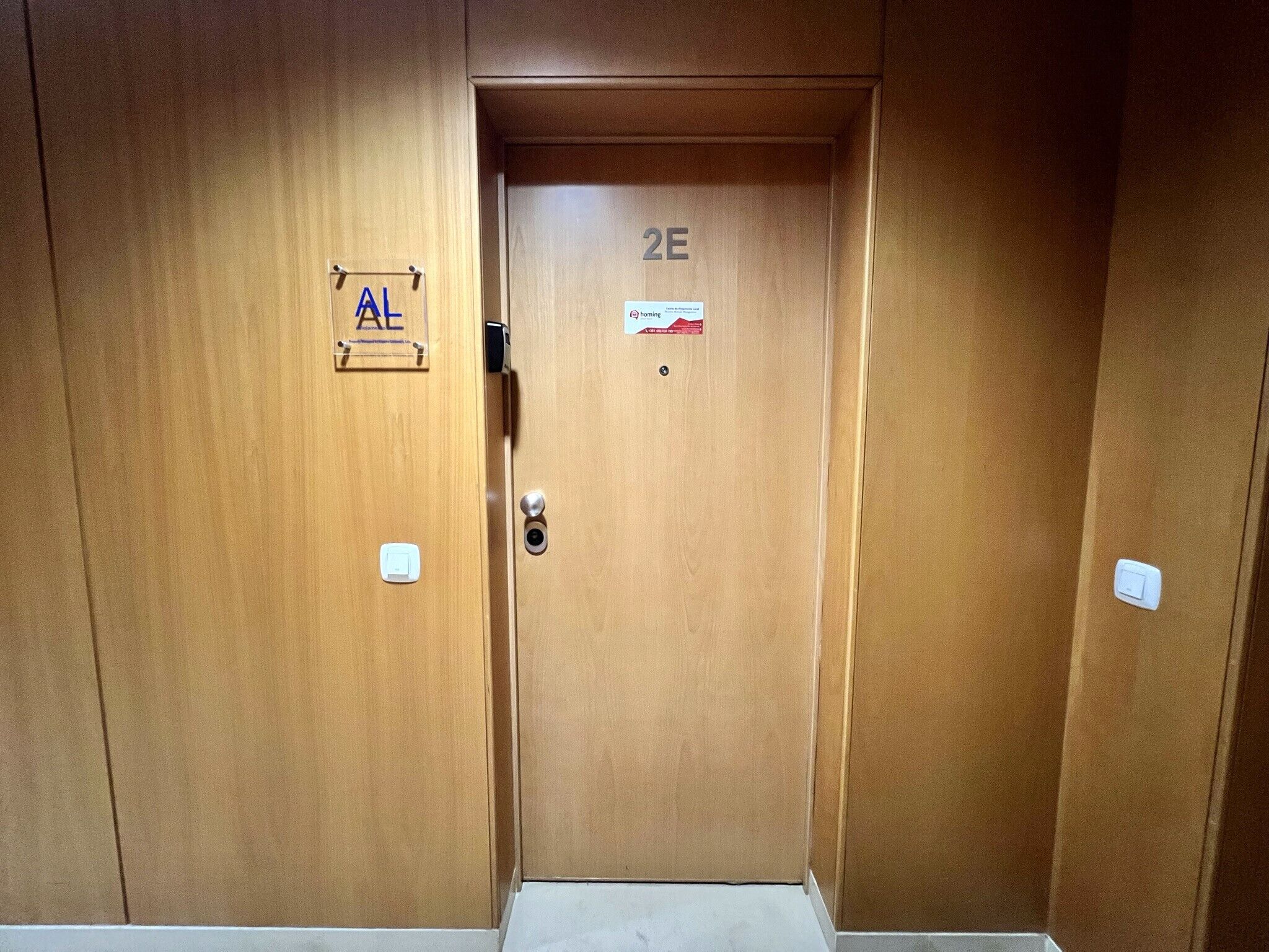 A wooden elevator door with a sign indicating '2E' and a small sign with 'AL' on the left side.