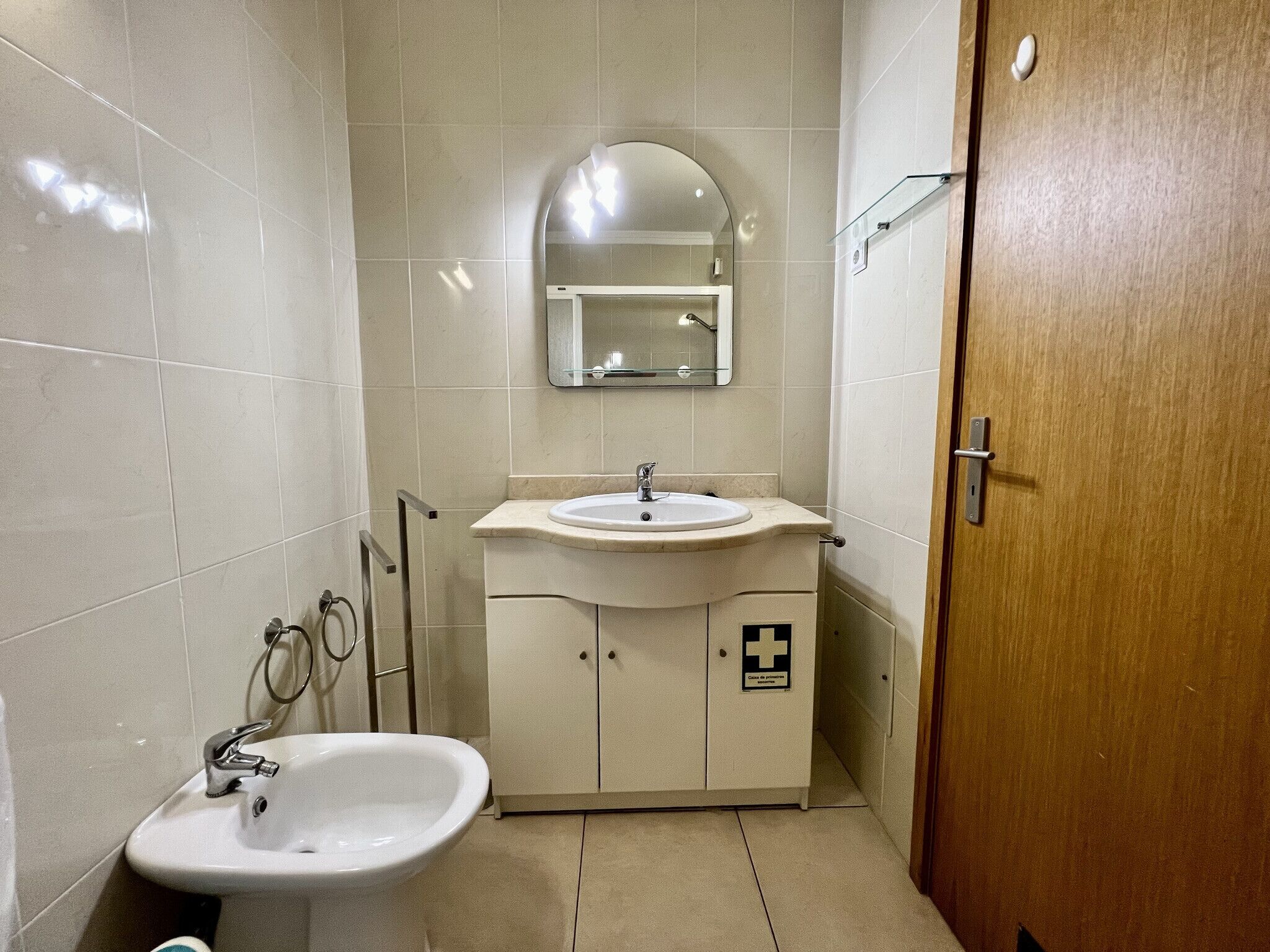 Een compacte badkamer met een wastafel, spiegel en kast.