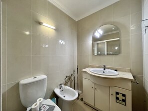 Ein Badezimmer mit Toilette, Bidet, Waschbecken und Spiegel.