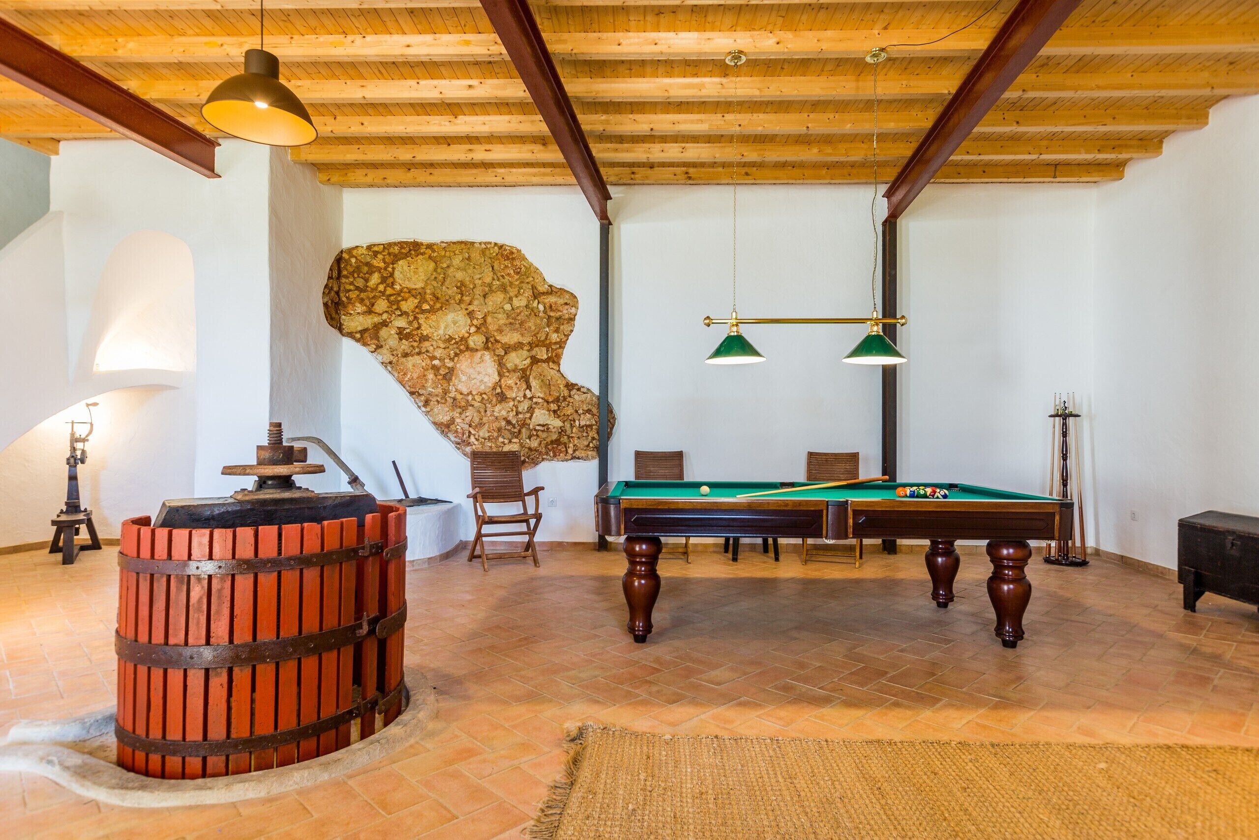Ein Billardraum mit Pooltisch, Stühlen, einem Holzfass und einer Steinwand.