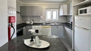 A modern kitchen with a granite countertop, white appliances, and a window above the sink.
