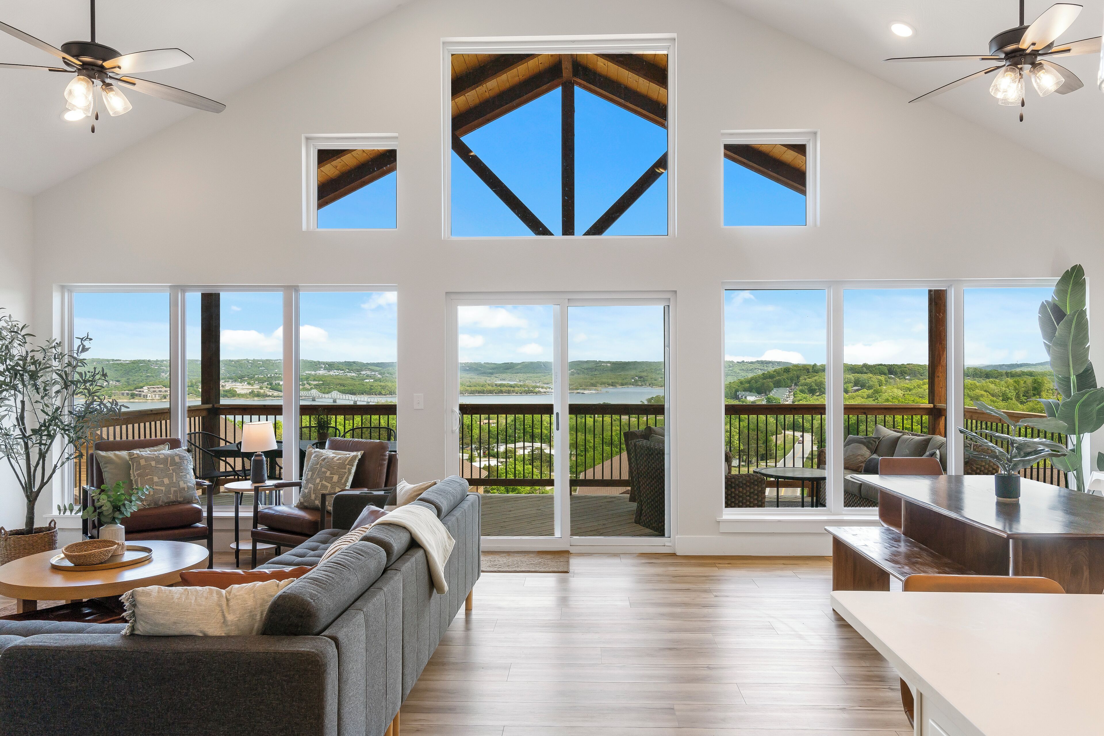 A spacious living room with a large sliding glass door leading to a balcony with a scenic view.
