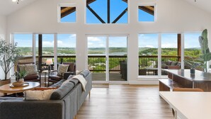 A spacious living room with a large sliding glass door leading to a balcony with a scenic view. - The Table Rocker • Ozark Family Retreat, 5BR 7 BA (Kimberling City)