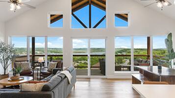 A spacious living room with a large sliding glass door leading to a balcony with a scenic view.