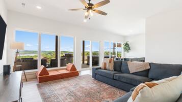 A spacious living room with a large gray sofa, a patterned rug, and a ceiling fan.