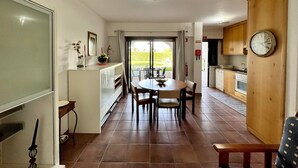 A modern kitchen with a dining area, a wooden cabinet, and a clock on the wall. - Vilamoura SEA Village by Homing (Loulé)
