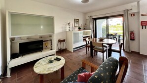 A living room with a TV, a dining table, and a sofa. - Vilamoura SEA Village by Homing (Loulé)