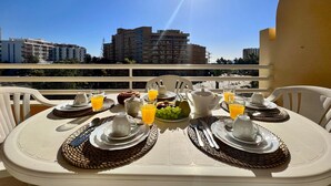 A breakfast table set with plates, cups, and glasses, overlooking a cityscape. - Vilamoura Marina MAR 2 With Pool (Loulé)