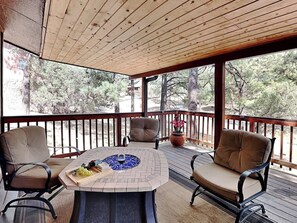 A covered outdoor seating area with a round table, two chairs, and a potted plant. - Indianhead Lodge by Ruidoso Vacation Rentals (Ruidoso)
