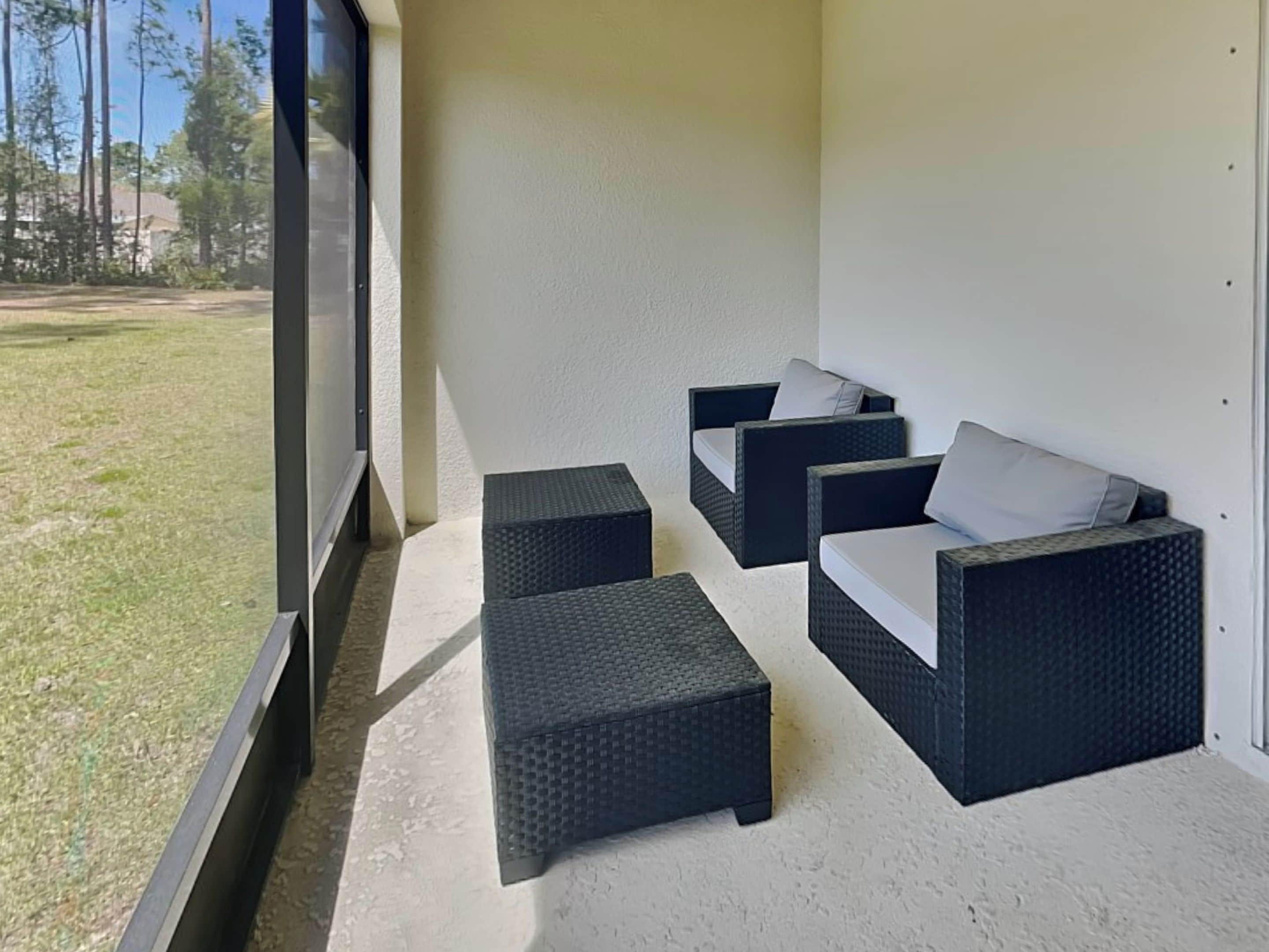 Un espace extérieur aménagé, abrité et doté de meubles en osier, avec vue sur une pelouse.