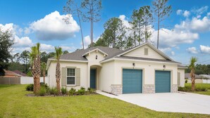 A single-story house with a front garage, a small porch, and a well-maintained lawn. - Breezy Villa by Distinctive Beach Rentals (Palm Coast)
