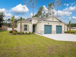 A single-story house with a front garage, a small porch, and a well-maintained lawn. - Breezy Villa by Distinctive Beach Rentals (Palm Coast)