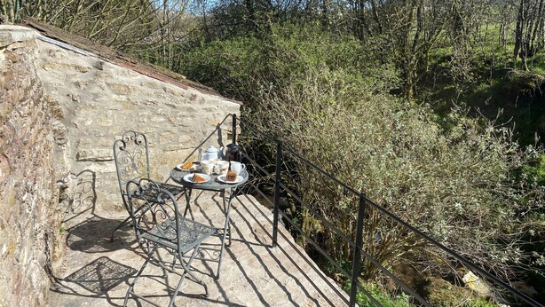 A stone wall with a metal table and chairs, a kettle, and a cup set on a ledge overlooking a forested area. - Spacious detached holiday home, sleeps 7 with 2 furry friends, free WiFi, two pubs nearby. (Richmond)