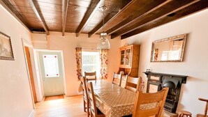 A dining room with a wooden table and chairs, a fireplace, and a mirror on the wall. - Spacious detached holiday home, sleeps 7 with 2 furry friends, free WiFi, two pubs nearby. (Richmond)