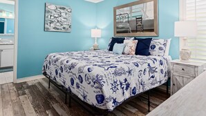 A bedroom with a bed, a ceiling fan, a nightstand, a mirror, and a window with blinds. - Turtle's Nest by Miss Kitty’s (Rockport)