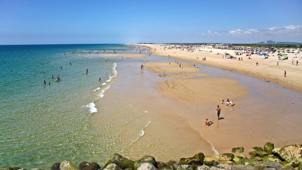 A beach with clear water, sandy shore, and rocks in the foreground. - Tavira Vila Formosa 5 With Pool (Tavira)