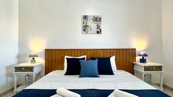 A neatly made bed with a wooden headboard, two bedside tables with lamps, and a wall art piece above the bed.