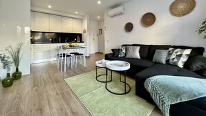 Un salon moderne avec un canapé noir, une table basse et un coin repas comprenant une table et des chaises.