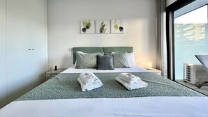 Une chambre d’hôtel moderne avec un lit bien fait, une tête de lit verte et une fenêtre donnant sur des immeubles.