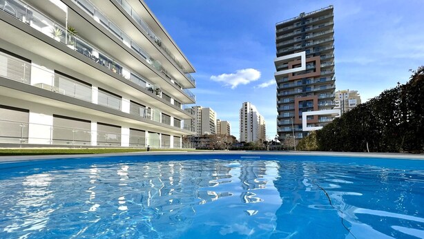 Un bâtiment moderne avec une piscine devant.