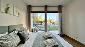 Une chambre d’hôtel moderne avec un grand lit, une vue sur le parking et un balcon doté d’une balustrade.