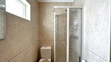 A bathroom with a toilet, a shower with a glass door, and a towel rack.