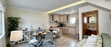 Un espace de vie compact comprenant un coin repas, une kitchenette et un canapé.