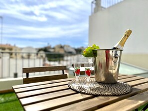 A metal bucket with a bottle of champagne, two glasses with strawberries, and a woven placemat on a wooden table outdoors. - Carvoeiro Terrace by Homing (Lagoa)