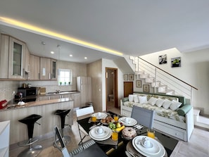 A modern kitchen with a dining area, a staircase, and a living room with a sofa. - Carvoeiro Terrace by Homing (Lagoa)