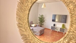 A modern living room with a sofa, a coffee table, a TV, a plant, and a decorative mirror.