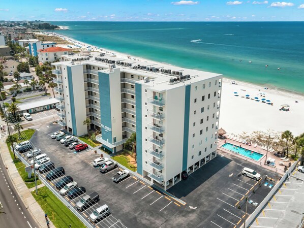 Ein mehrgeschossiges Hotel mit Pool und Blick auf den Strand, einem Parkplatz und einem Schild mit der Aufschrift 'SEA BREEZE'.