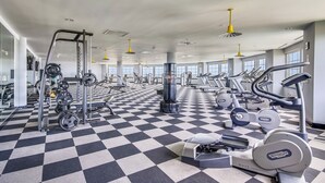 A gym with a checkered floor, various exercise equipment, and large windows.
